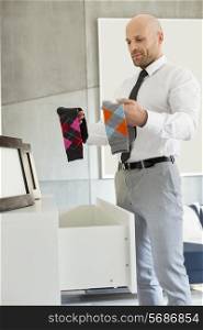 Mid adult businessman selecting socks at home