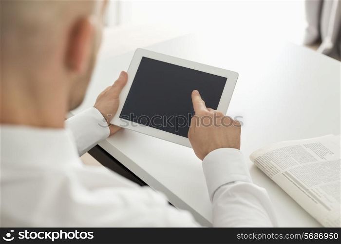 Mid adult businessman using digital computer at table in home office