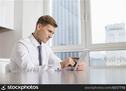 Mid adult businessman using digital tablet at kitchen table