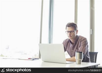 Mid-adult businessman using laptop at desk in creative office