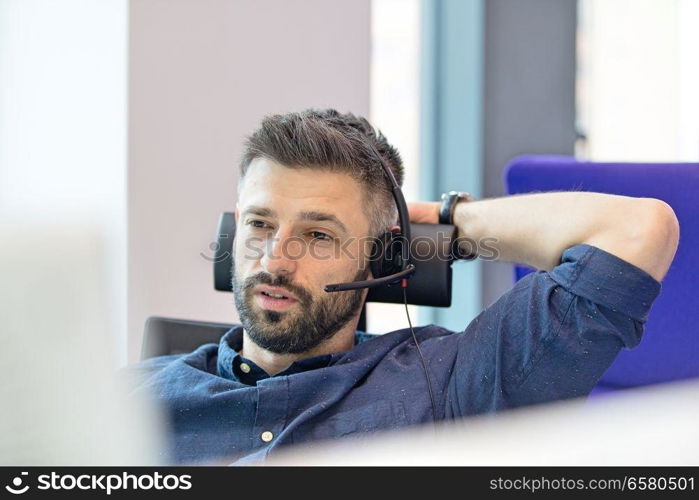 Mid adult businessman wearing telephone headset in office