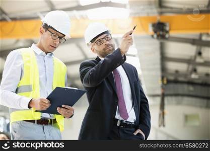 Mid adult businessman with supervisor having discussion in metal industry