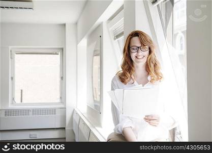 Mid adult businesswoman reading paperwork in office