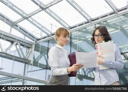 Mid-adult businesswoman showing document to female colleague in office