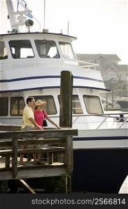 Mid-adult Caucasian couple at dock with boat in background.