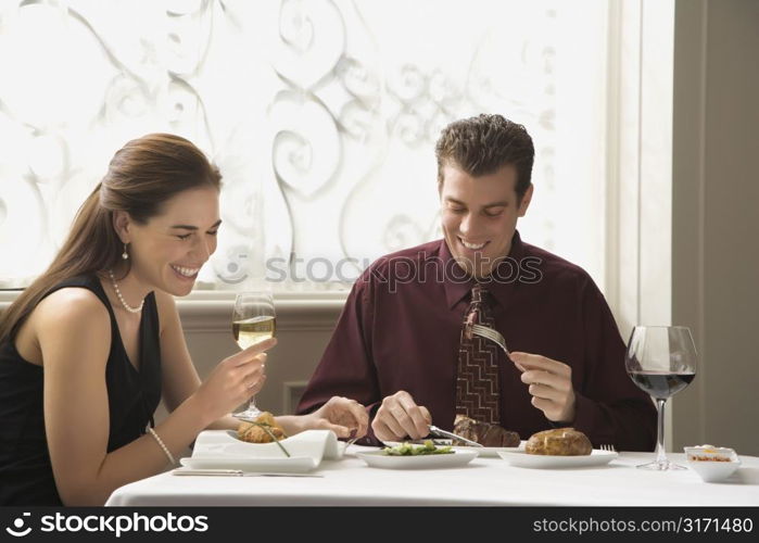 Mid adult Caucasian couple dining in restaurant and laughing.