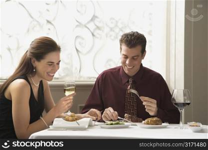 Mid adult Caucasian couple dining in restaurant and laughing.