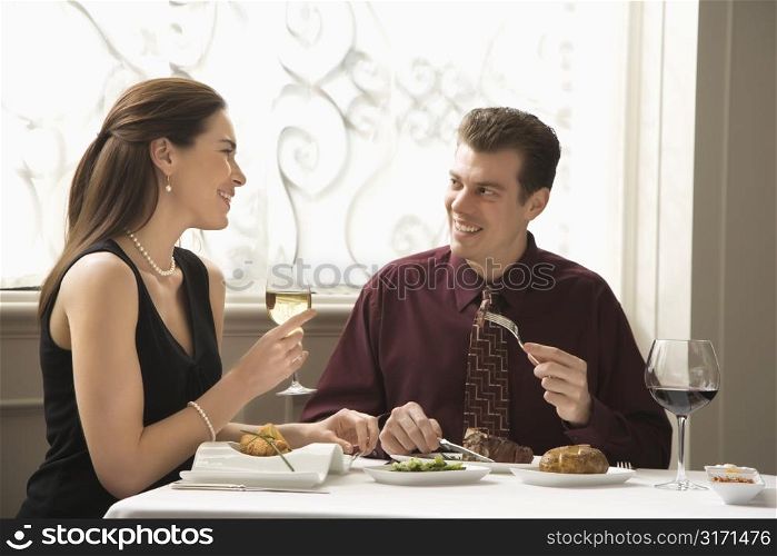 Mid adult Caucasian couple dining in restaurant and smiling.