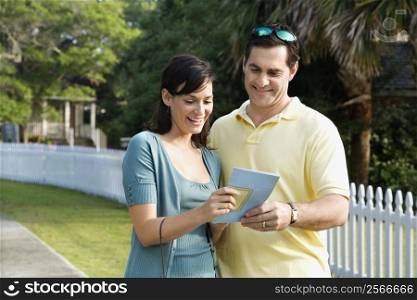 Mid-adult Caucasian couple holding a map and smiling.