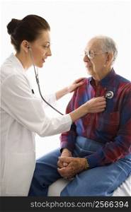 Mid-adult Caucasian female doctor listening to elderly Caucasian male&acute;s heart with stethoscope.