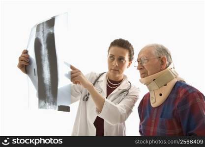 Mid-adult Caucasian female doctor ponting at x-ray with elderly Caucasian male in neck brace looks on.