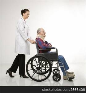 Mid-adult Caucasian female doctor pushing elderly Caucasian male with neck brace in wheelchair.