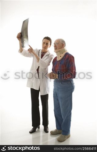 Mid-adult Caucasian female doctor showing x-ray to elderly Caucasian male in neck brace.