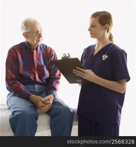 Mid-adult Caucasian female in scrubs taking notes from elderly Caucasian male.