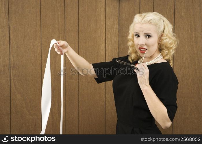 Mid-adult Caucasian female in vintage outfit holding a printout and eye glasses.