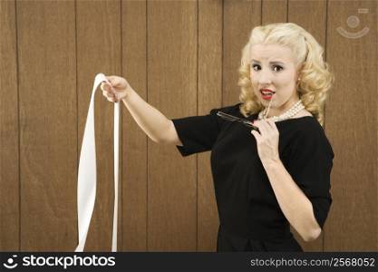 Mid-adult Caucasian female in vintage outfit holding a printout and eye glasses.