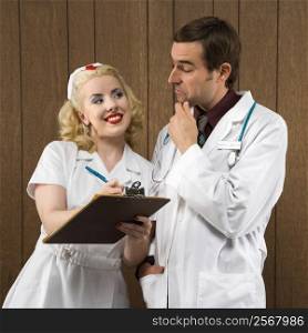 Mid-adult Caucasian female nurse smiling at male doctor making facial expression.