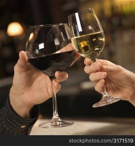 Mid adult Caucasian male and female hands toasting wine glasses.