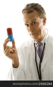 Mid-adult Caucasian male doctor holding an oversized medical pill.