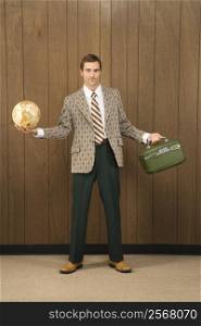Mid-adult Caucasian male in retro suit holding luggage and a globe.