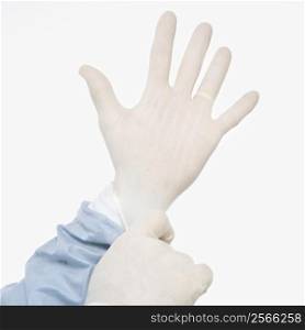 Mid-adult Caucasian male putting on latex medical gloves.