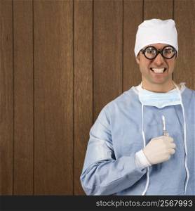 Mid-adult Caucasian male surgeon wearing thick glasses and holding scalpel smiling maniacally.