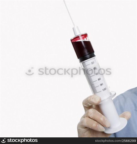 Mid-adult Caucasian male wearing latex medical gloves and holding a syringe.