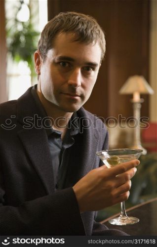 Mid adult Caucasian man holding martini and looking at viewer.