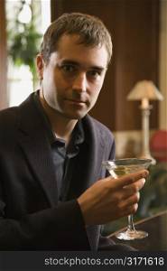 Mid adult Caucasian man holding martini and looking at viewer.