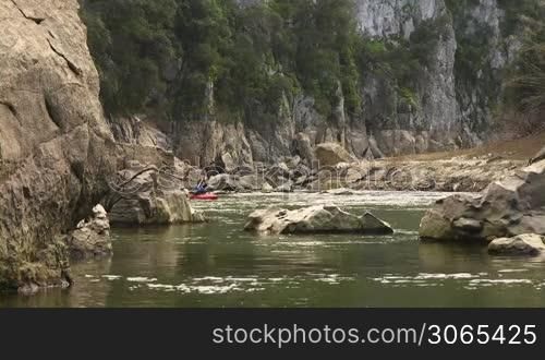 Mid adult caucasian man on red kayak paddling on river during leisure activity