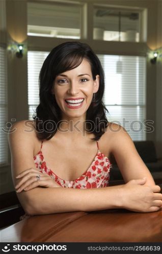 Mid-adult Caucasian woman sitting at bar smiling.