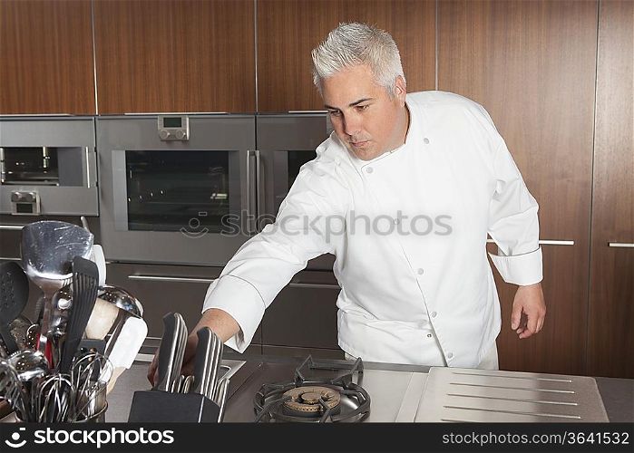 Mid adult chef leans for knife