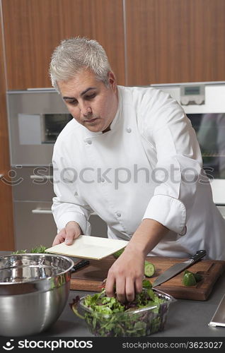 Mid- adult chef prepares salad