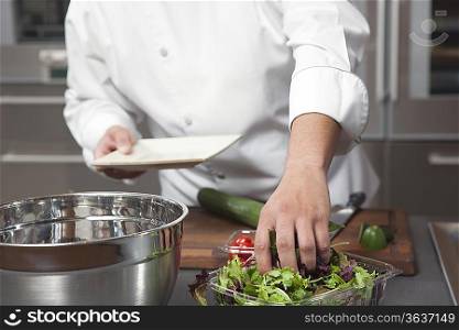 Mid- adult chef prepares salad