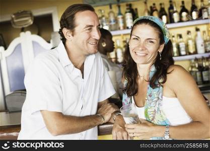 Mid adult couple at a bar counter and smiling