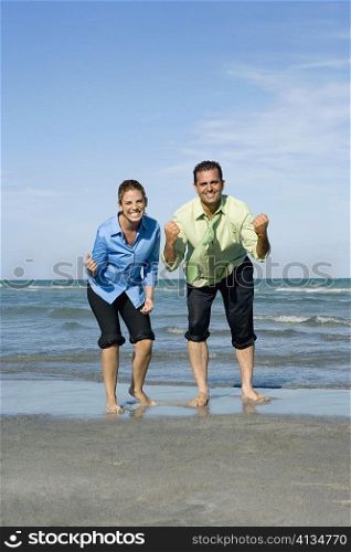 Mid adult couple clenching their fists on the beach
