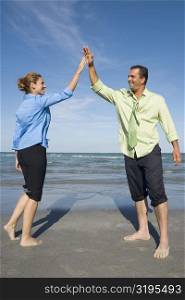 Mid adult couple giving high-five to each other and smiling