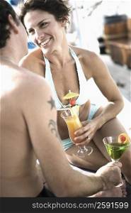 Mid adult couple holding glasses of cocktail and looking at each other