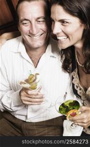 Mid adult couple holding glasses of cocktail and smiling