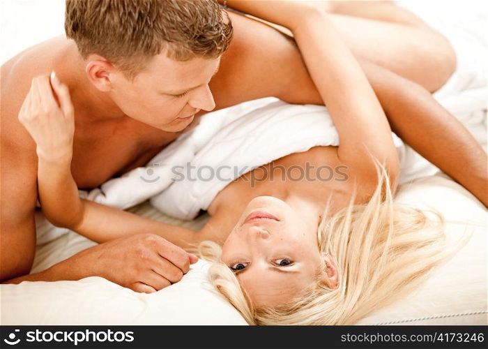 Mid adult couple in bed as woman looks at camera