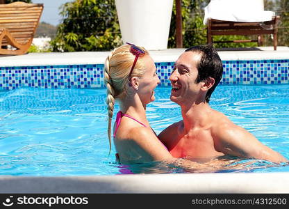 Mid adult couple in outdoor pool, laughing