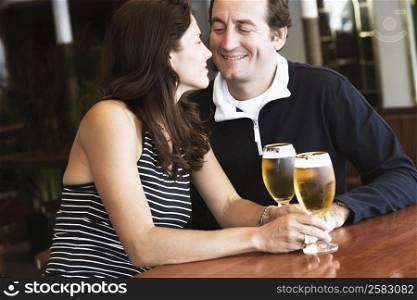 Mid adult couple looking at each other and holding beer in stem glasses