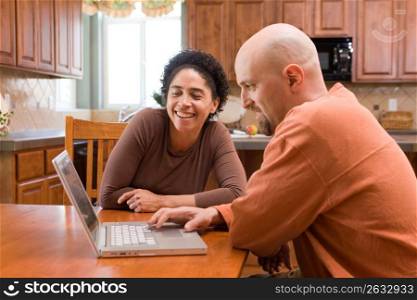 Mid adult couple looking at laptop, smiling