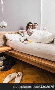 Mid adult couple lying in bed, breakfast on tray