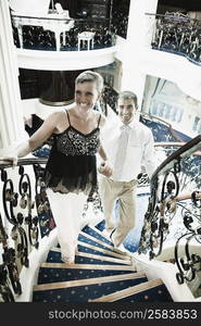 Mid adult couple moving up on a staircase of a cruise ship and smiling