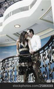 Mid adult couple romancing at a balcony of a ship