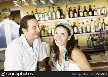 Mid adult couple sitting at a bar counter and smiling