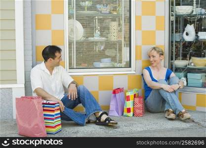 Mid adult couple sitting at a sidewalk and smiling