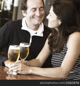 Mid adult couple sitting in a bar and holding beer in stem glasses