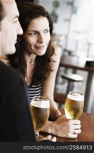 Mid adult couple sitting in a bar and holding beer in stem glasses